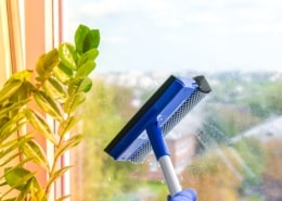 Employee hand in rubber protective glove cleans window with foam and puller. General spring cleaning