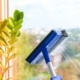 Employee hand in rubber protective glove cleans window with foam and puller. General spring cleaning