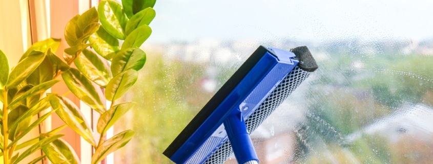 Employee hand in rubber protective glove cleans window with foam and puller. General spring cleaning