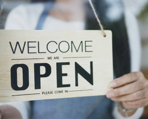 Close up of woman hands holding sign now we are open support local business.