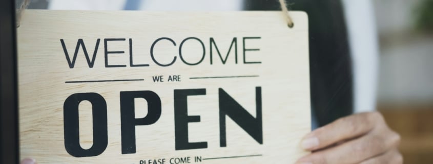 Close up of woman hands holding sign now we are open support local business.