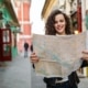 Cheerful woman searching direction on location map while traveling