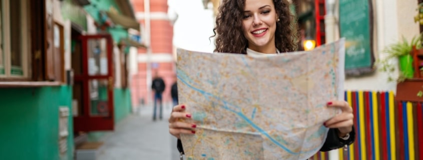 Cheerful woman searching direction on location map while traveling