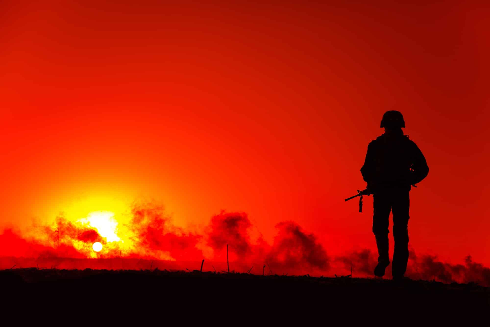 Army soldier walking on battlefield at sunset
